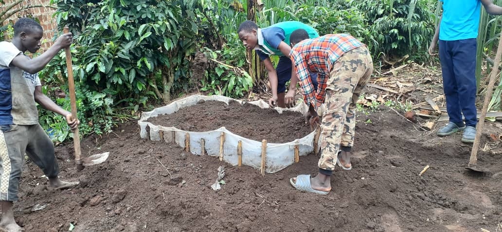 Young people working together to prepare a community garden bed in Uganda